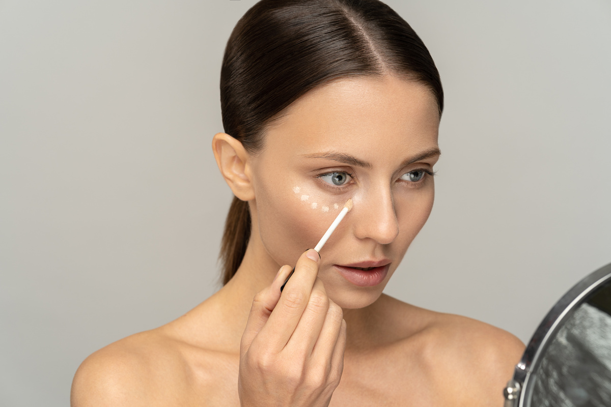 Woman with Natural Makeup Applying Concealer on  Skin